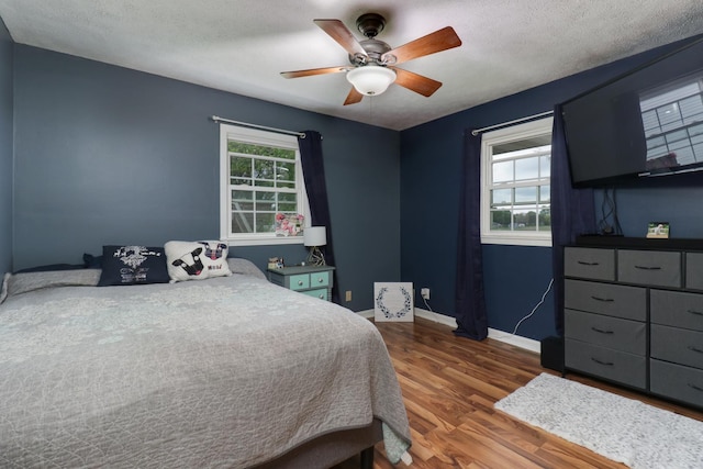 bedroom featuring wood finished floors, baseboards, ceiling fan, and a textured ceiling
