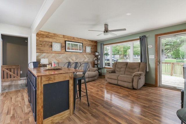 living room with a ceiling fan, an accent wall, wooden walls, and light wood-style flooring
