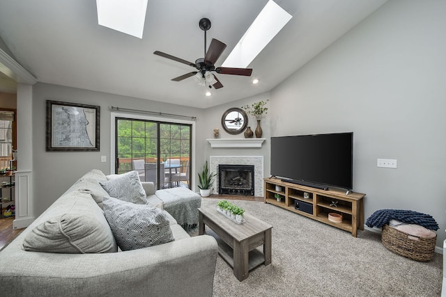 carpeted living area with a skylight, a fireplace, a ceiling fan, lofted ceiling, and recessed lighting