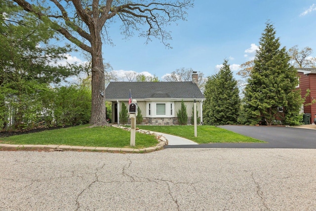 view of front facade featuring a chimney, stone siding, and a front lawn