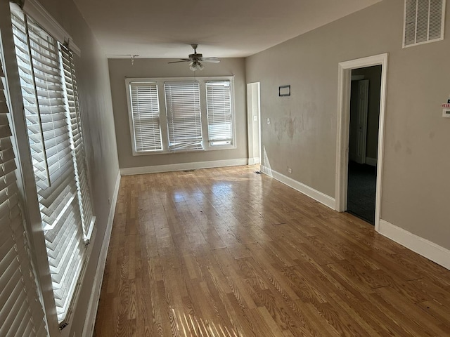 unfurnished room featuring visible vents, baseboards, a ceiling fan, and wood-type flooring