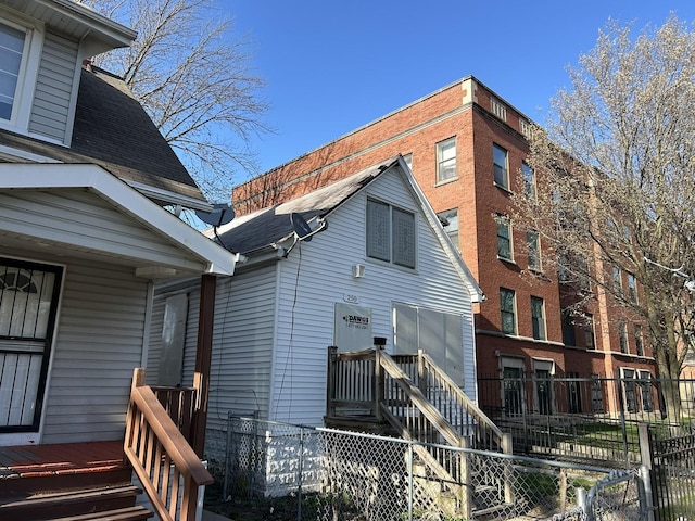 rear view of house with a shingled roof and fence