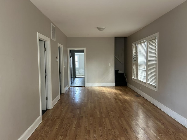 spare room with baseboards, stairway, visible vents, and wood finished floors