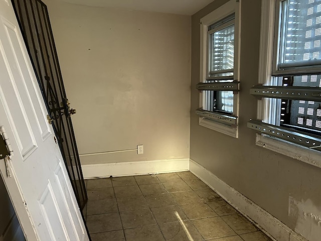 spare room featuring baseboards and dark tile patterned floors