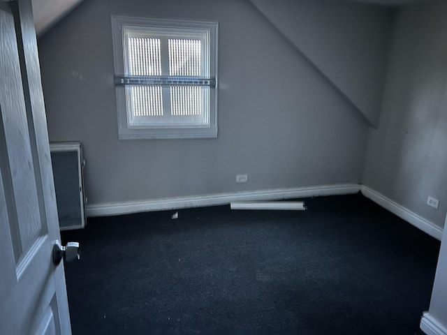 bonus room with baseboards, dark carpet, and vaulted ceiling
