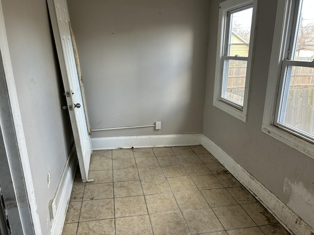 spare room featuring light tile patterned floors and baseboards