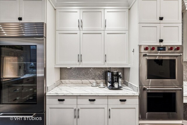 kitchen featuring white cabinetry, decorative backsplash, refrigerator, and stainless steel double oven