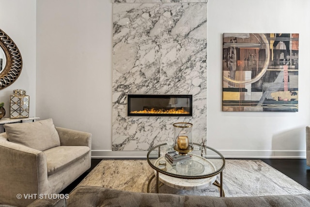 living room featuring baseboards, a high end fireplace, and wood finished floors