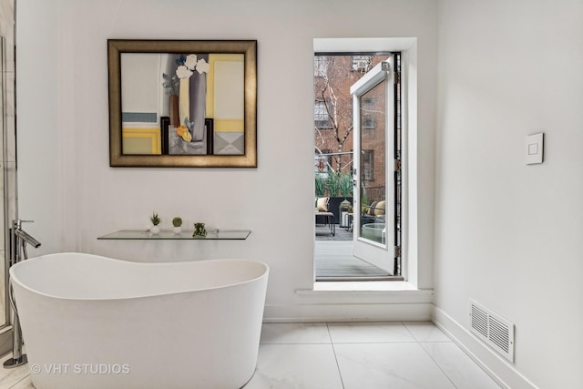 interior space with a freestanding bath, baseboards, and visible vents