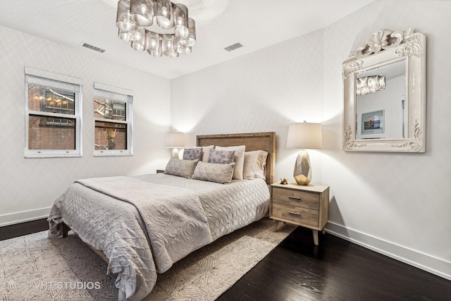 bedroom with an inviting chandelier, visible vents, baseboards, and wood-type flooring