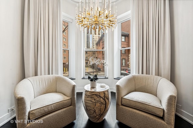 sitting room with an inviting chandelier, a wealth of natural light, baseboards, and wood finished floors