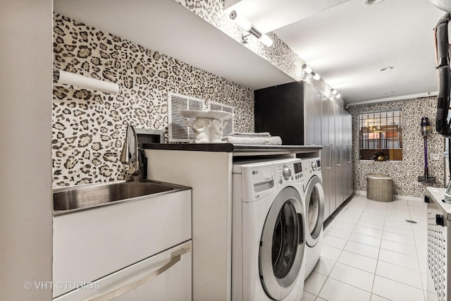 clothes washing area with washing machine and dryer, light tile patterned floors, a sink, laundry area, and wallpapered walls