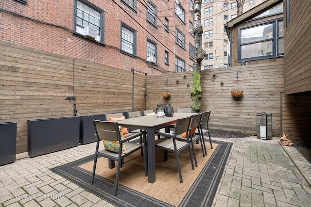 view of patio featuring cooling unit, outdoor dining area, and a fenced backyard