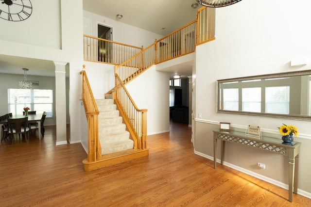 131 Glenbrook Cir, Gilberts, IL 60136 - stairway featuring baseboards, wood finished floors, a towering ceiling, and a notable chandelier