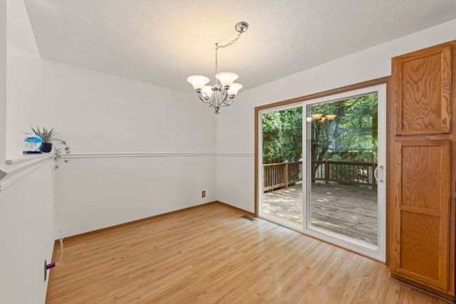 726 Hawthorne Ln, Genoa, IL 60135 - unfurnished room with light wood finished floors, a chandelier, and a textured ceiling