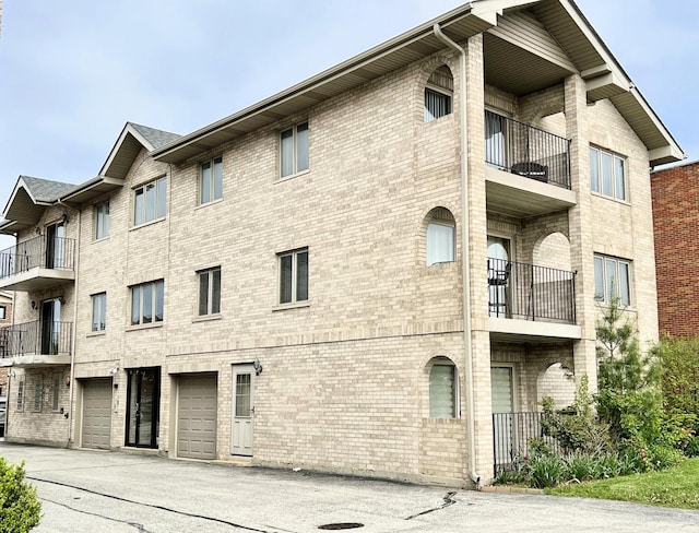 view of apartment building / complex with an attached garage and driveway