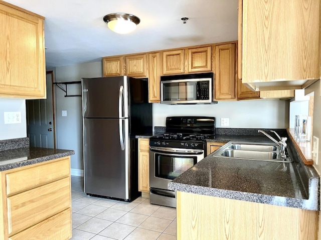 kitchen featuring stainless steel appliances, a sink, light tile patterned flooring, and light brown cabinetry
