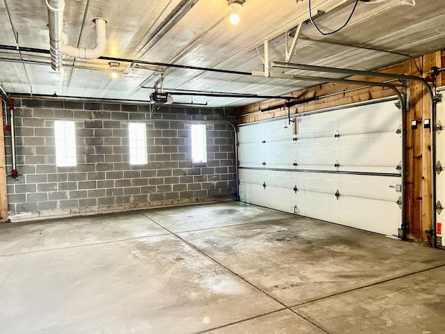garage featuring concrete block wall and a garage door opener