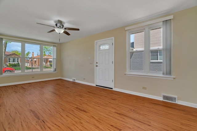 unfurnished living room with a ceiling fan, wood finished floors, and baseboards