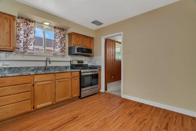kitchen with stainless steel appliances, a sink, light wood-style flooring, and healthy amount of natural light