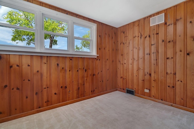 carpeted empty room featuring wooden walls