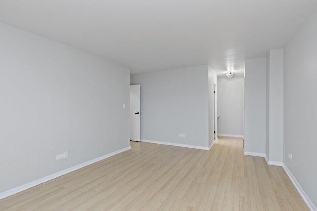 empty room featuring light wood finished floors and baseboards