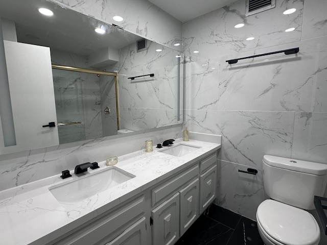 bathroom featuring toilet, marble look tiles, a marble finish shower, and double vanity