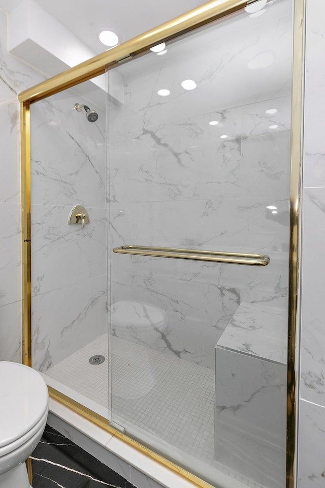 bathroom with a marble finish shower and toilet