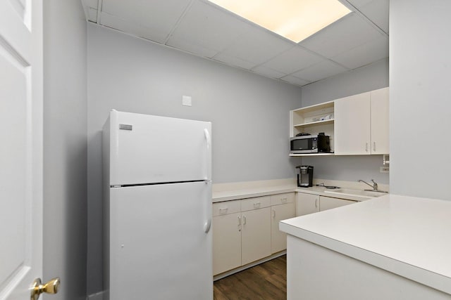 kitchen with freestanding refrigerator, stainless steel microwave, open shelves, light countertops, and dark wood-type flooring