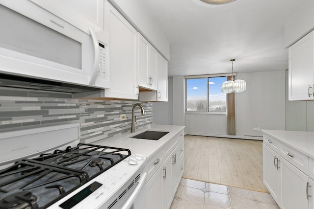 kitchen with white appliances, a baseboard heating unit, a sink, white cabinets, and decorative backsplash