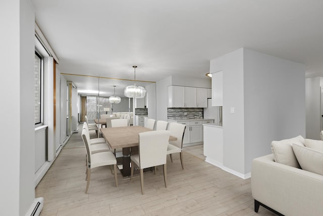 dining area with light wood-style floors, baseboard heating, a chandelier, and baseboards