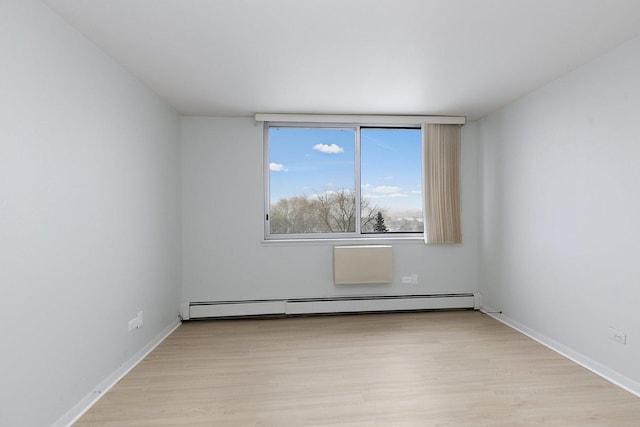spare room featuring light wood-type flooring, baseboard heating, and baseboards