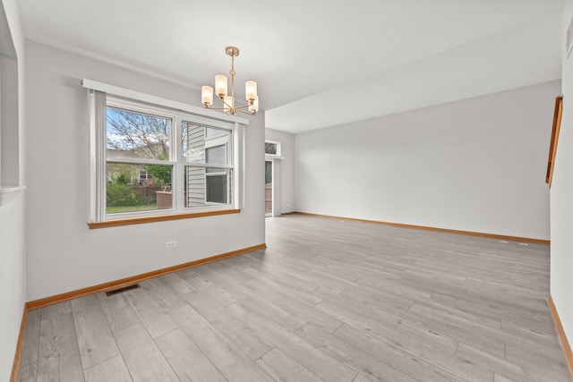 empty room featuring a chandelier, baseboards, and wood finished floors
