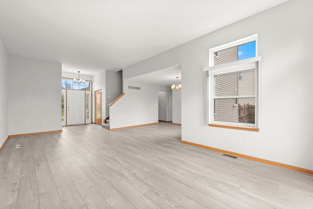 unfurnished living room with a chandelier, baseboards, and light wood-type flooring