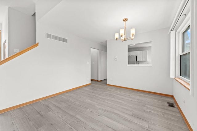 unfurnished room featuring a chandelier, light wood-style flooring, and baseboards