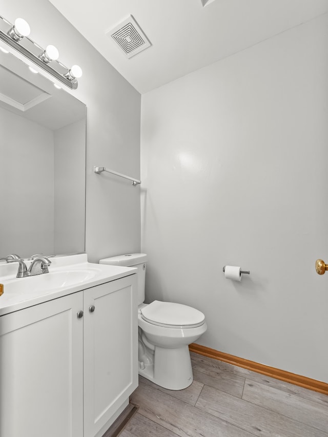 bathroom featuring wood finished floors, toilet, vanity, and baseboards