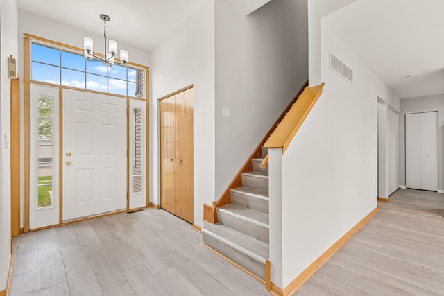 entryway featuring a chandelier, wood finished floors, stairs, and baseboards