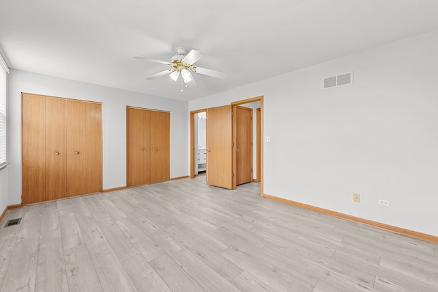 unfurnished bedroom with baseboards, light wood-style flooring, multiple closets, and ceiling fan