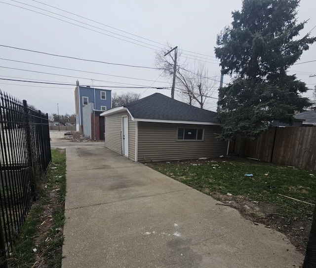 5321 W Crystal St, Chicago, IL 60651 - view of side of property with an outdoor structure, driveway, fence, and roof with shingles