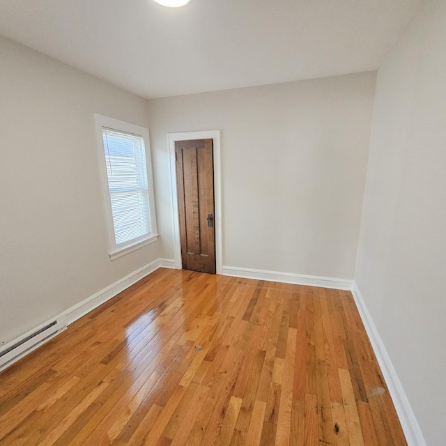 5321 W Crystal St, Chicago, IL 60651 - empty room with light wood-style floors, baseboards, and a baseboard heating unit