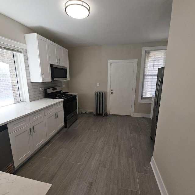5321 W Crystal St, Chicago, IL 60651 - kitchen featuring radiator, light stone counters, dark wood finished floors, white cabinetry, and appliances with stainless steel finishes