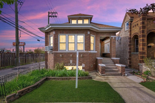 bungalow with a yard, brick siding, and fence
