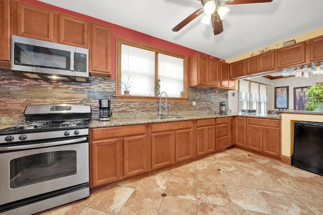 kitchen with ceiling fan, a sink, decorative backsplash, brown cabinets, and appliances with stainless steel finishes