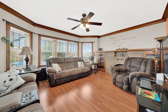 living area with a fireplace, ceiling fan, crown molding, and light wood-type flooring