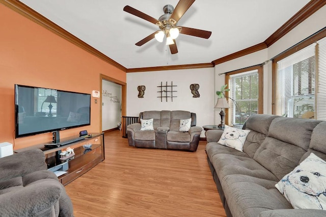 living area with ornamental molding, light wood-style flooring, baseboards, and ceiling fan