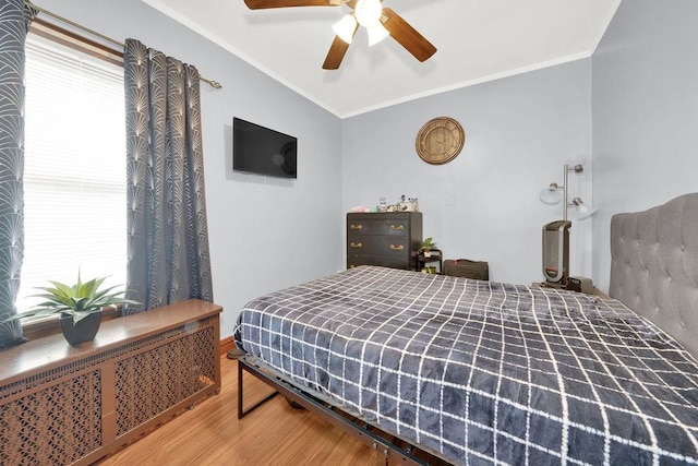 bedroom featuring wood finished floors, a ceiling fan, crown molding, lofted ceiling, and radiator heating unit