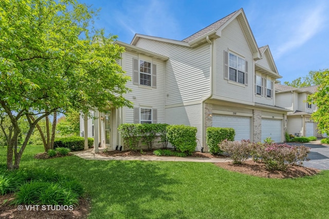 view of front of property featuring an attached garage, a front yard, and asphalt driveway