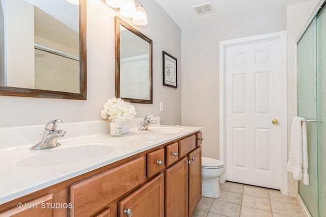 bathroom featuring tile patterned floors, double vanity, toilet, and a shower with door