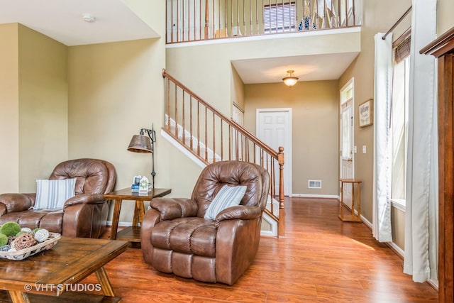 entryway with wood finished floors, stairs, baseboards, and a high ceiling