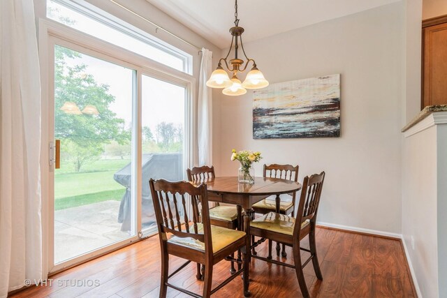 dining space featuring light wood finished floors, a chandelier, and baseboards
